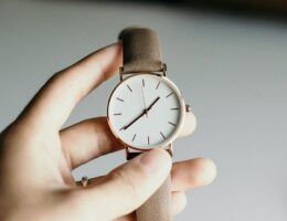 Hand håller upp ett armbandsur med brunt läderarmband