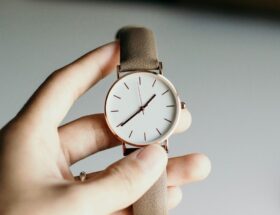 Hand håller upp ett armbandsur med brunt läderarmband