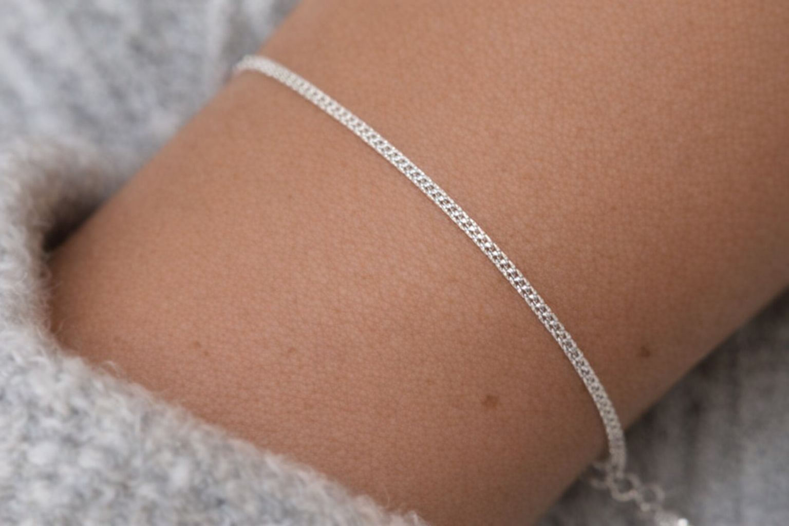 En närbild på ett tunt bismarckarmband i silver runt en handled.